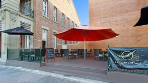 An outdoor seating area with tables and chairs, a red umbrella, and a sign for Regent Hotel. - Quality Hotel Regent Rockhampton (Rockhampton)