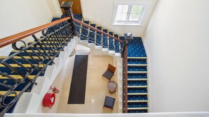 A staircase with blue carpeted steps, a wooden handrail, and a black metal railing. - Quality Hotel Regent Rockhampton (Rockhampton)