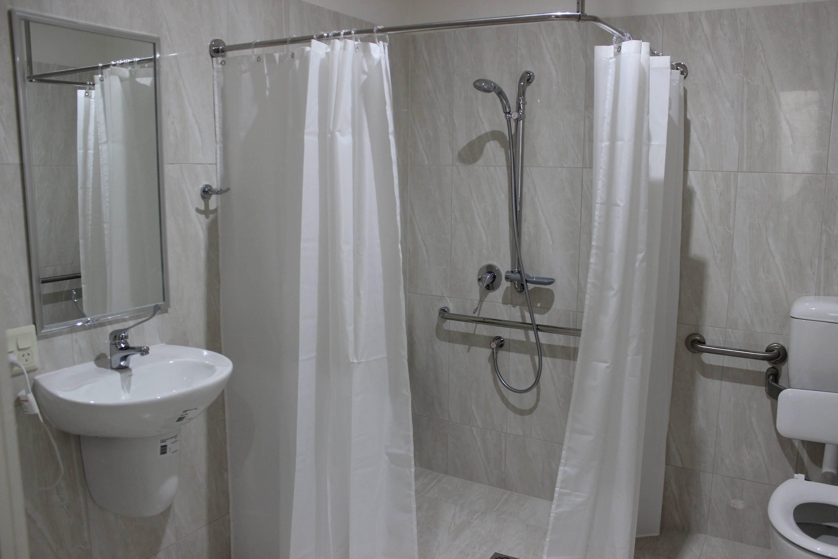 Une salle de bain moderne avec une douche à parois de verre, un lavabo blanc et des toilettes.