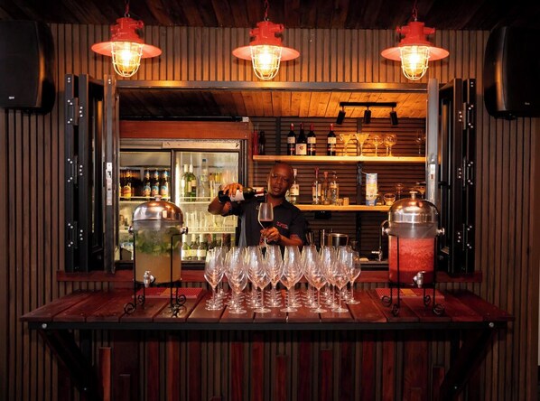 A bar area with a wooden counter, multiple wine glasses, and a refrigerator stocked with bottles. - Onomo Hotel Dar es Salaam (Dar es Salaam)