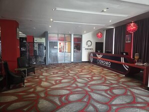 Un hall de hotel con mostrador de recepción, zona de estar y alfombra estampada.