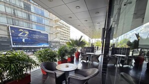Un área de estar al aire libre con sillas y mesas de mimbre, rodeada de plantas en macetas.