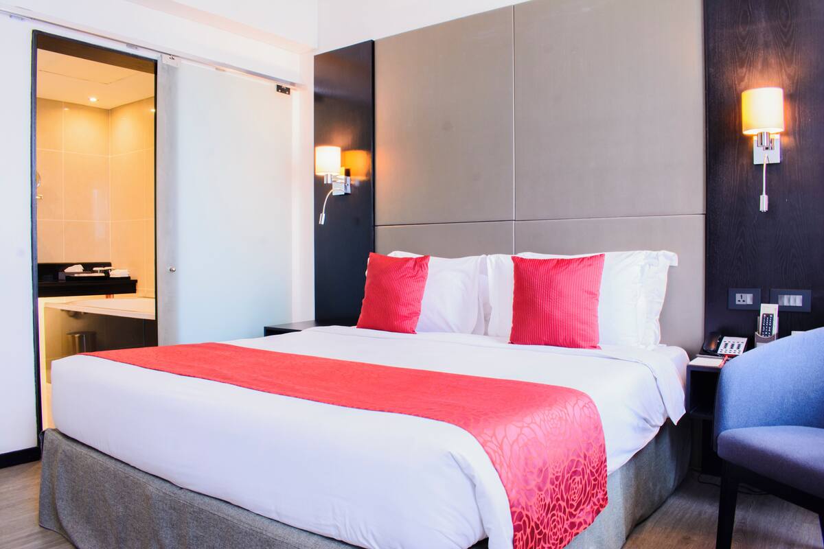 Una habitación de hotel con una cama, un escritorio con teléfono y una silla.
