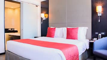 Una habitación de hotel con una cama, un escritorio con teléfono y una silla.