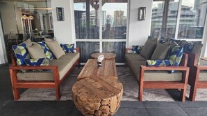 Un área de descanso moderna con dos sofás, una mesa baja central y un detalle decorativo de piedra.