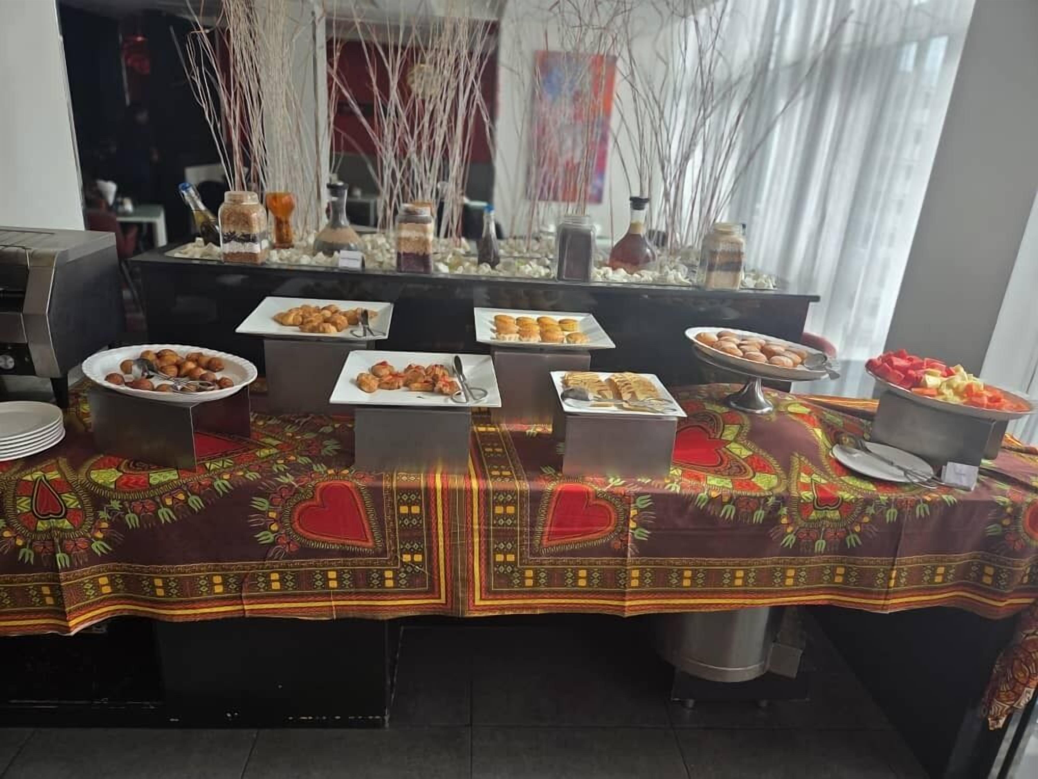 A buffet table with various food items and a decorative tablecloth.