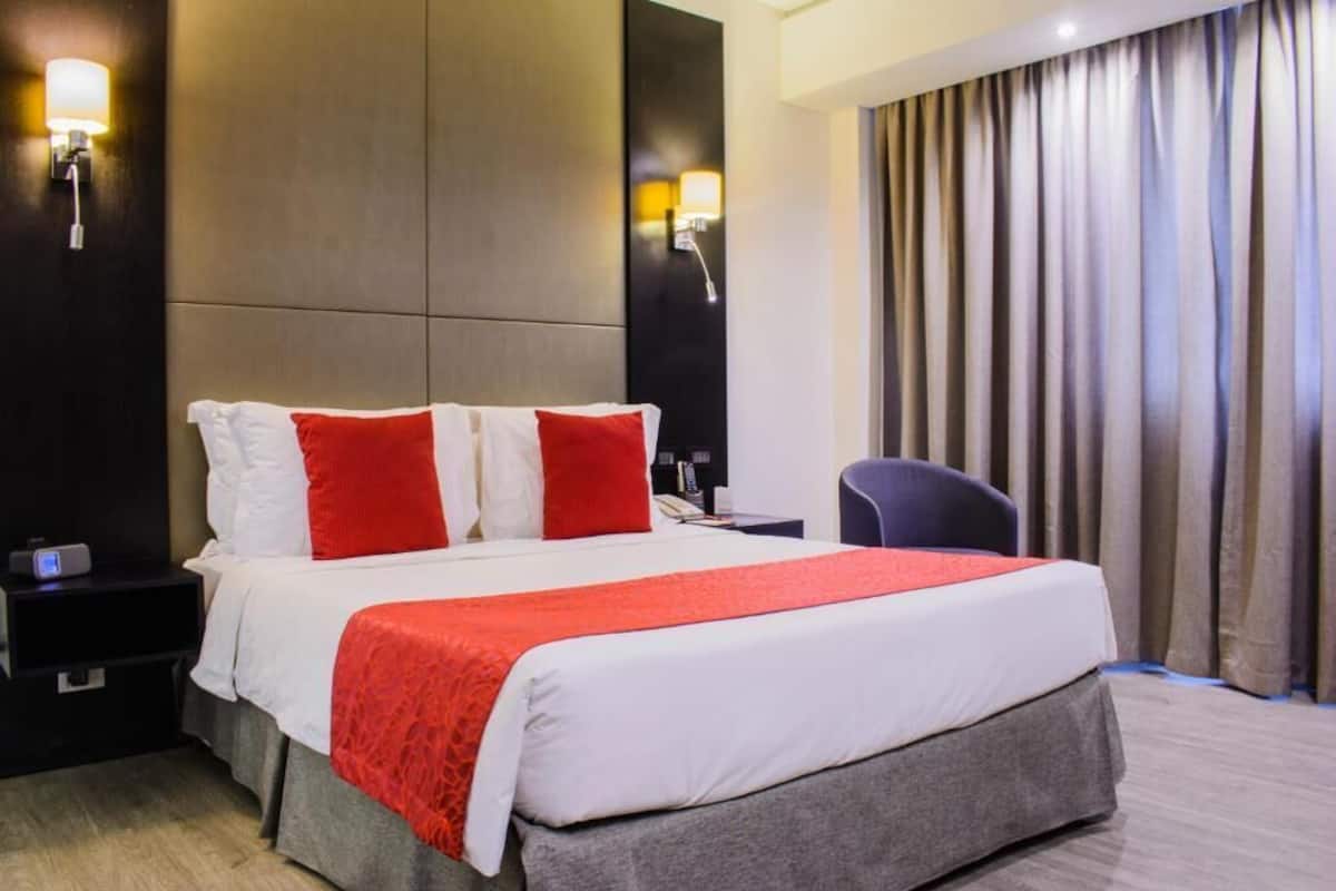 Una habitación de hotel con una cama grande, dos mesitas de noche, un escritorio y una silla.