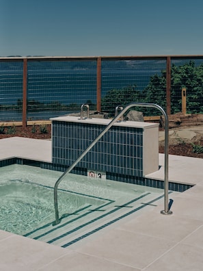 Una piscina con una escalera de metal, un letrero de no buceo y vista al mar.