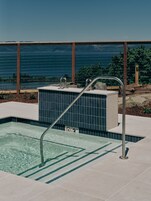 Una piscina con una escalera de metal, un letrero de no buceo y vista al mar.