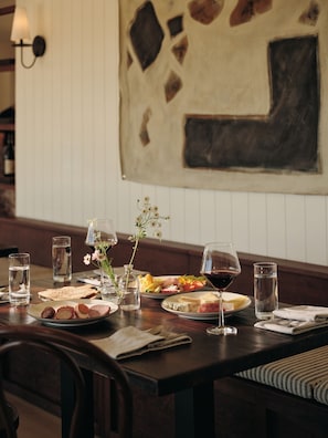 A dining table set with plates of food, glasses of water and wine, and a vase with flowers. - The Herondale Hotel (Astoria)
