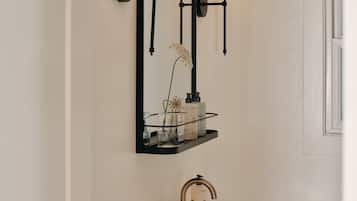 A bathroom with a white sink, black wall-mounted lights, and a mirror above the sink.