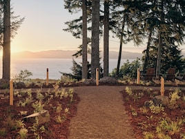 Un sendero conduce a una zona de estar con vistas al mar y a las montañas.