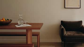 Un salón minimalista con una mesa de madera, un sillón de cuero marrón, un tapiz tejido y un cuadro enmarcado en la pared.