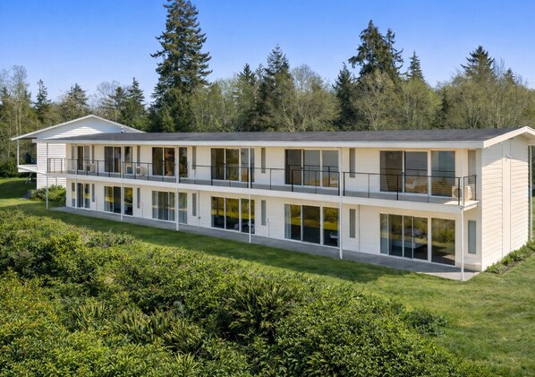 A modern two-story building with large windows and balconies, surrounded by greenery and trees. - The Herondale Hotel (Astoria)