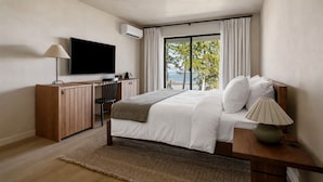 Une chambre moderne équipée d’un lit, d’un bureau, d’une télévision et offrant une vue sur l’extérieur.