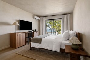 A modern bedroom with a bed, a desk, a TV, and a view of the outdoors. - The Herondale Hotel (Astoria)