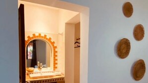 A hallway with a tiled floor leading to a bathroom with a sink and mirror. - L´hotelito (Tulum)