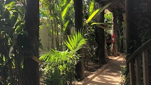 A covered pathway surrounded by lush greenery and potted plants. - L´hotelito (Tulum)