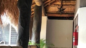 A covered outdoor area with a thatched roof, wooden pillars, and a fire extinguisher on the wall. - L´hotelito (Tulum)