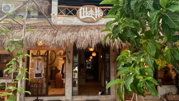 A hotel entrance with a thatched roof and a sign reading "Hotel to". - L´hotelito (Tulum)