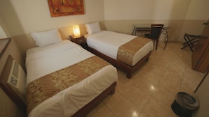 Quarto de hotel com duas camas, uma escrivaninha e uma cadeira.
