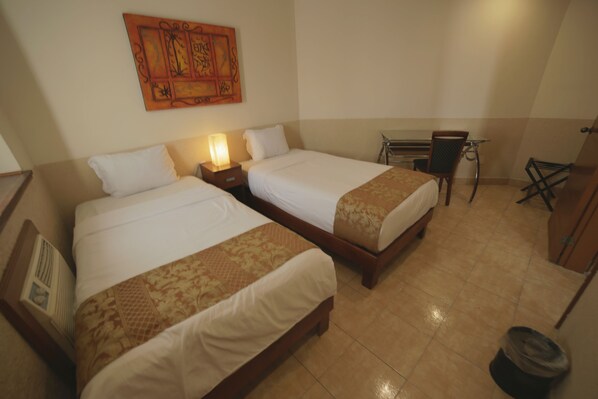 A hotel room with two beds, a desk, and a chair.