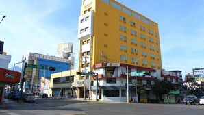 Um edifício amarelo com várias janelas e uma placa indicando 'Padre Mier'.