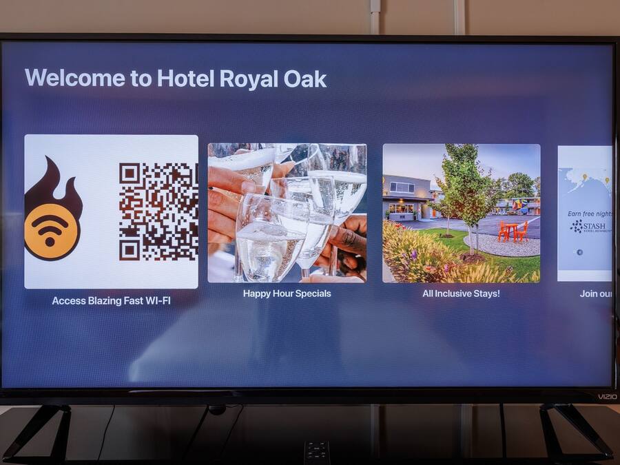 A welcome screen for Hotel Royal Oak with a Wi-Fi icon, a QR code, and images of a glass of water, a garden, and a map.