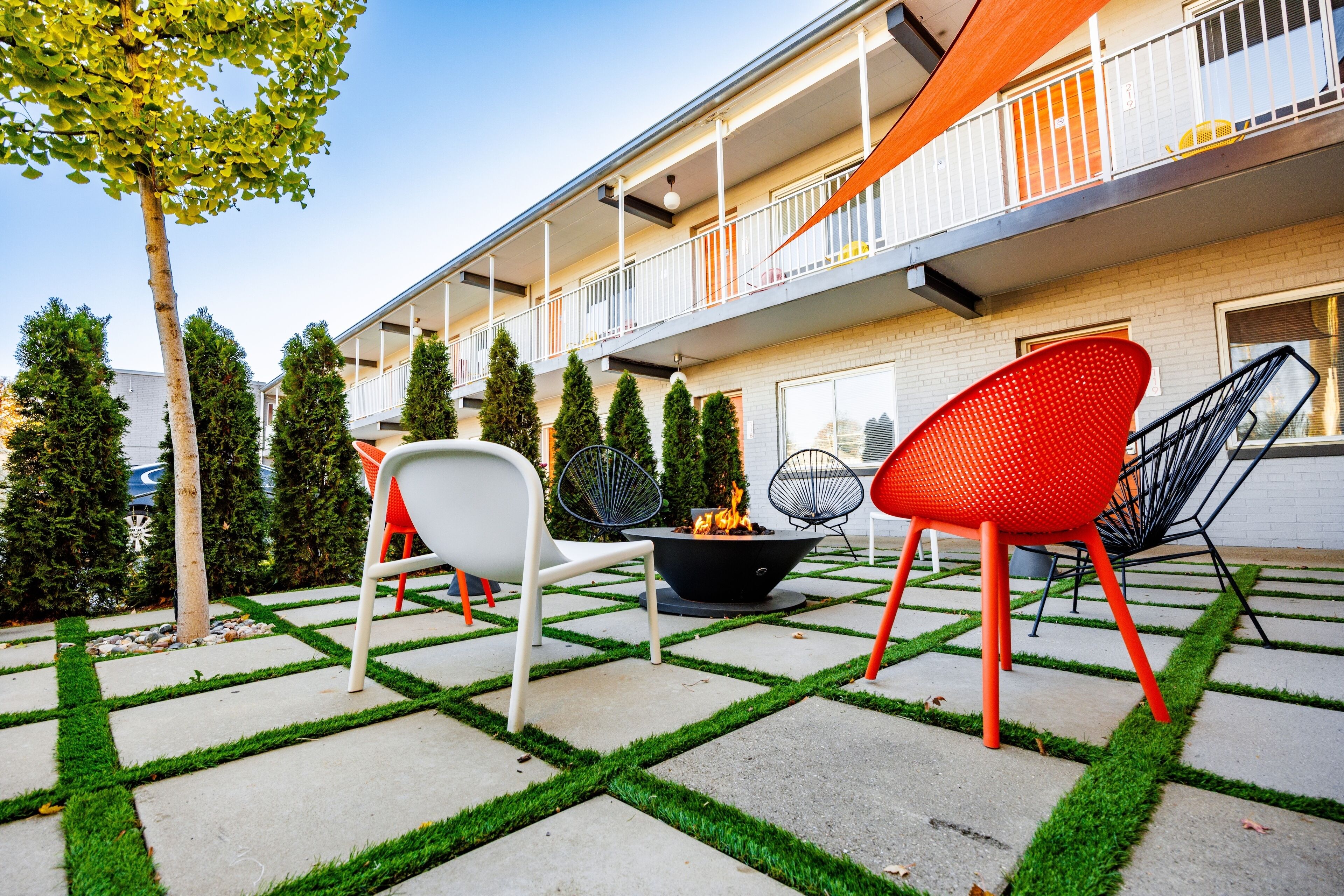 An outdoor patio with a fire pit, seating, and a building with a balcony.