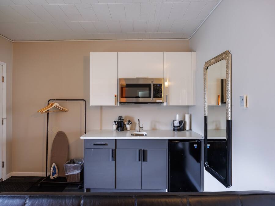 Una kitchenette compacta con microondas, lavamanos y armarios.