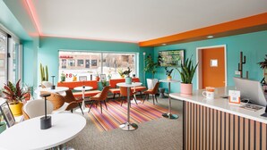 A modern hotel lobby with teal and orange walls, multiple seating areas, and a reception desk. - Hotel Royal Oak (Royal Oak)