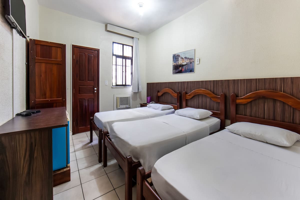 A hotel room with two beds, a desk, and a window.