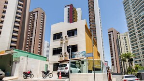 Un immeuble à plusieurs étages, doté d’une façade blanche, de plusieurs balcons et d’une marquise verte.