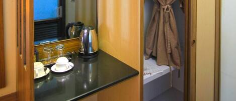 Una habitación compacta con kitchenette, un espejo y una bata colgada de una puerta.