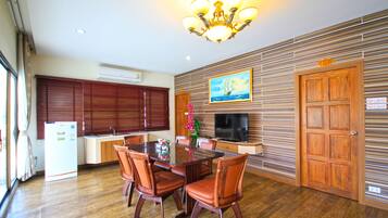 A modern kitchen with wooden cabinets, a dining table with chairs, a television, and a decorative painting on the wall.