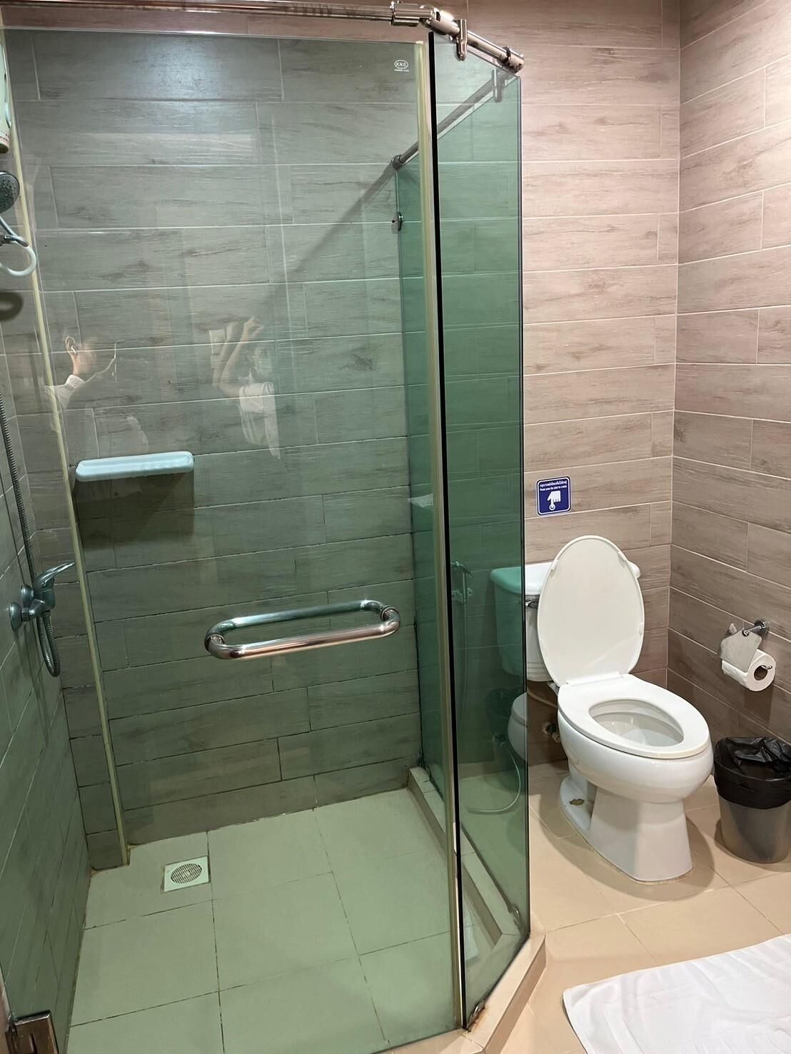 Un baño con ducha de mampara de vidrio, inodoro y lavamanos.