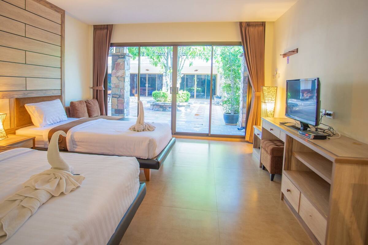 Habitación de hotel con dos camas, televisión y vista al exterior.