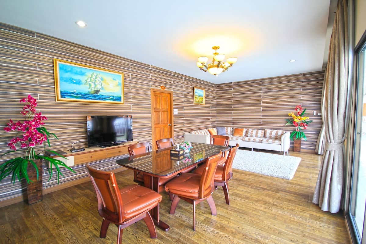 Una sala de estar moderna con piso de madera, una mesa de comedor con sillas, un sofá, un televisor y plantas decorativas.
