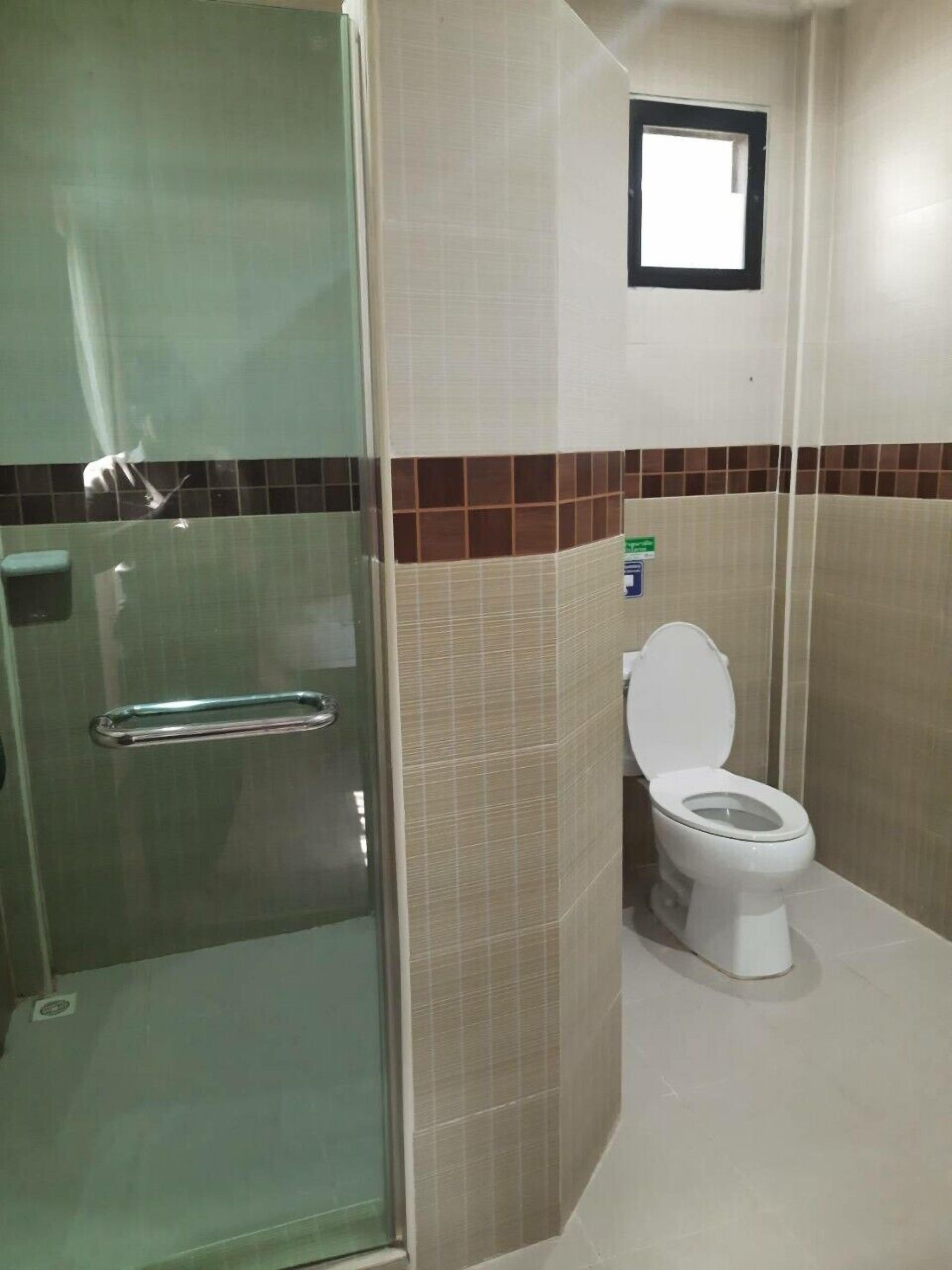 Ein Badezimmer mit Duschkabine, Toilette und kleinem Fenster.