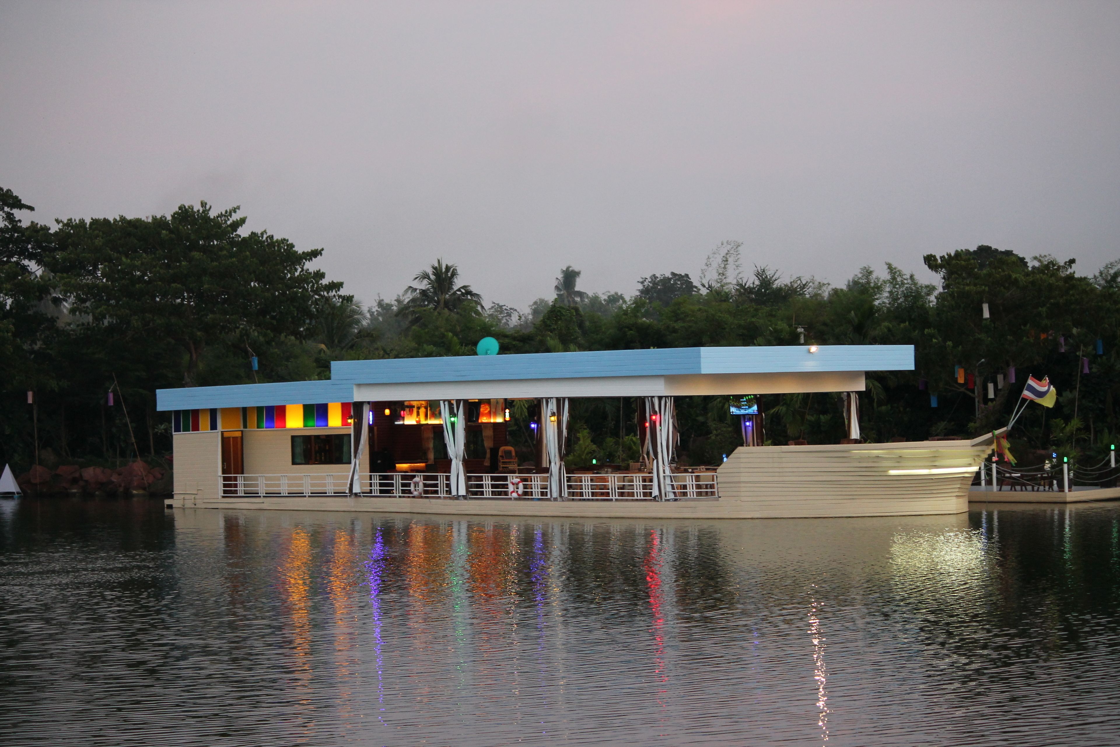 A waterfront building with a blue roof and a covered seating area.