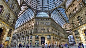 A spacious, ornate train station with a large glass roof and multiple arches.