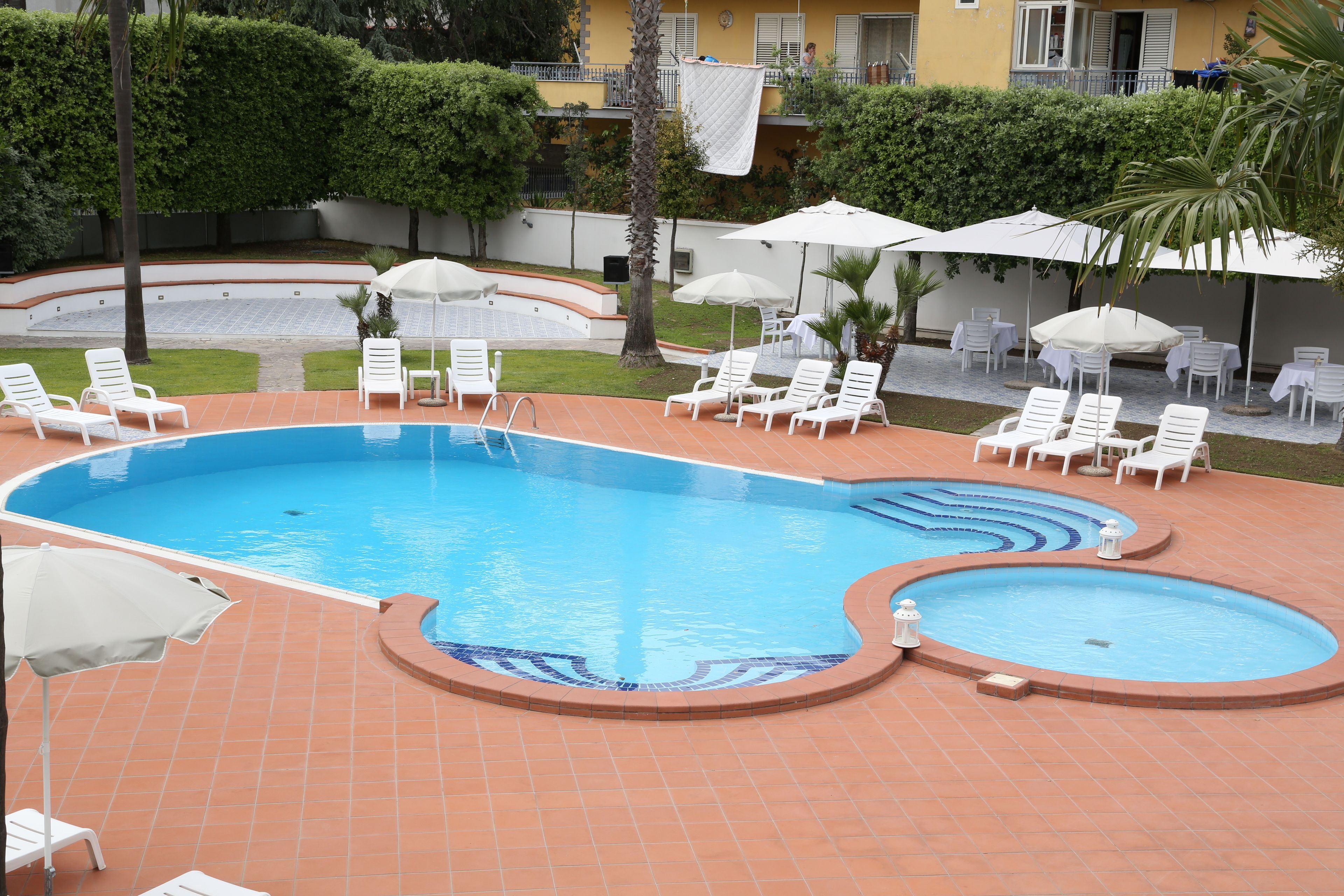 Une piscine entourée d’une terrasse carrelée, agrémentée de nombreuses chaises longues et de parasols.