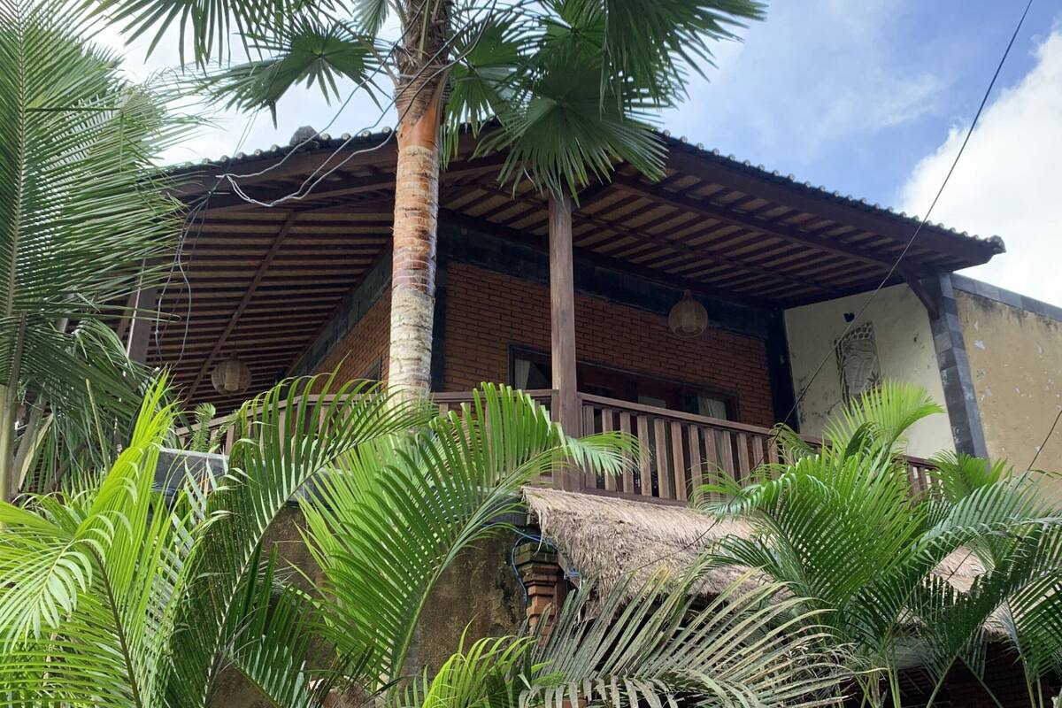 A rustic building with a thatched roof, surrounded by lush greenery.