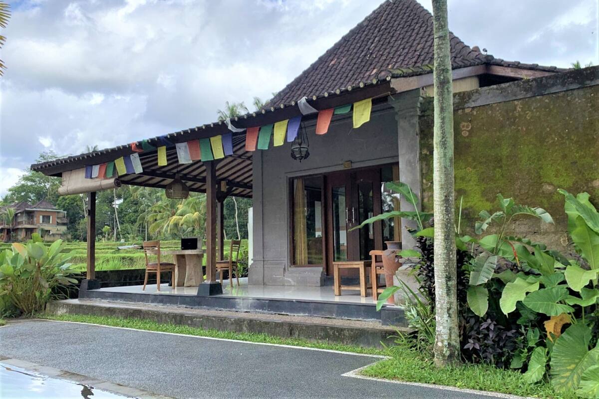 A building with a tiled roof, a covered porch, and a small outdoor seating area with chairs.