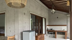 A spacious kitchen with a wooden table, a refrigerator, and a sink. - Bagiya Suites & Villas (Ubud)