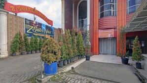 L’entrée d’un hôtel, avec une grande enseigne indiquant « Z Suites Hotel » et une banderole pour « Z Suites Hotel » faisant la publicité d’une garantie de satisfaction à 100 %.