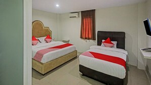 Une chambre d’hôtel avec deux lits, chacun doté de draps rouges et blancs, d’une tête de lit en bois, d’une table de chevet, d’un téléviseur et d’un appareil de climatisation.