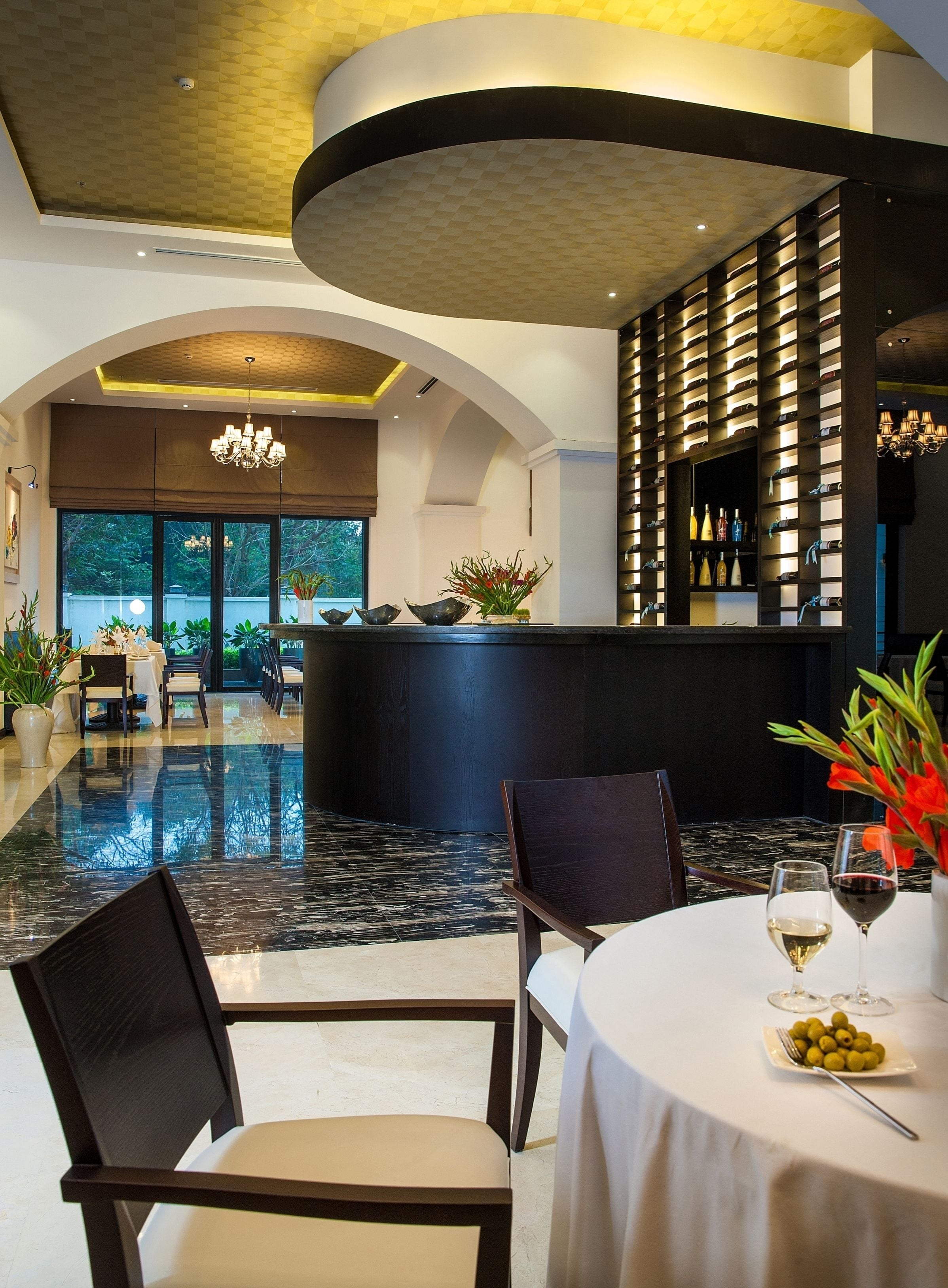 A restaurant with a curved ceiling, a bar area with shelves of bottles, and a dining area with tables and chairs.