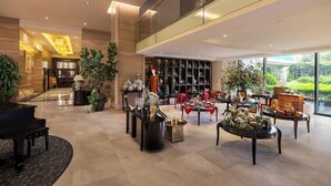Un vestíbulo amplio con un piano de cola, una gran estantería y diversos objetos decorativos.