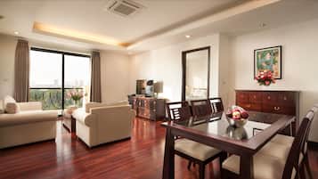 A spacious living room with a wooden floor, a dining area with a glass table, and a balcony with a city view.
